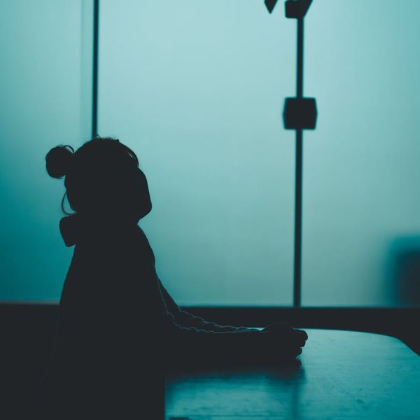 Woman in a calm and strong pose against a dark background with pink light.